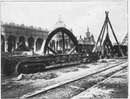 Avant l'ouverture.- 1.Déchargement d'un volant de grande taille (Champ-de-Mars).1900年博 開幕前 － 1.大車輪の荷降ろし（シャン・ド・マルス会場）