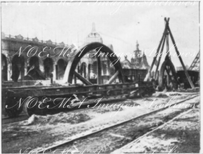 Avant l'ouverture.- 1.Déchargement d'un volant de grande taille (Champ-de-Mars).1900年博 開幕前 － 1.大車輪の荷降ろし（シャン・ド・マルス会場）